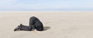A business man, hiding his head in the sand.